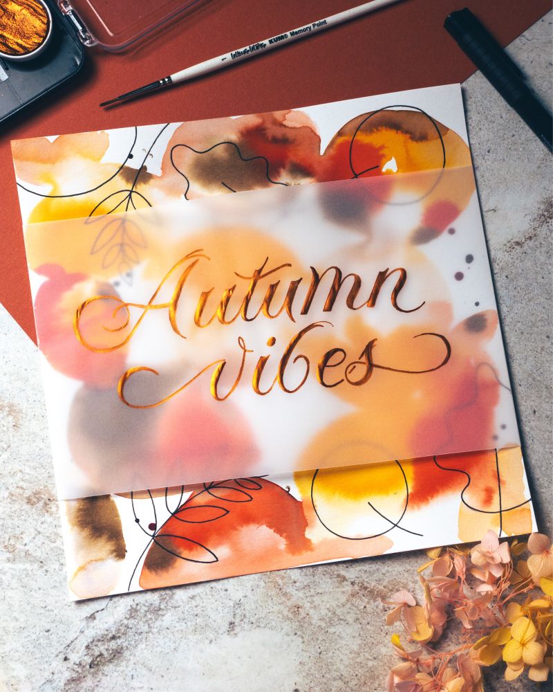 Handlettered words „autumn vibes“ on a watercolor background in autumn colors