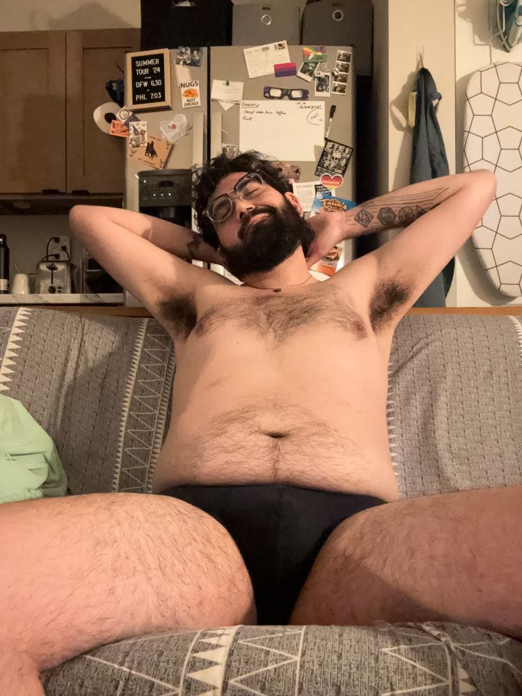 it's me again! i'm sitting on the couch and leaning back, with my hands behind my head and my arms up. i'm only wearing a pair of black trunk underwear, so my hairy chest, stomach, legs, and pits are all visible