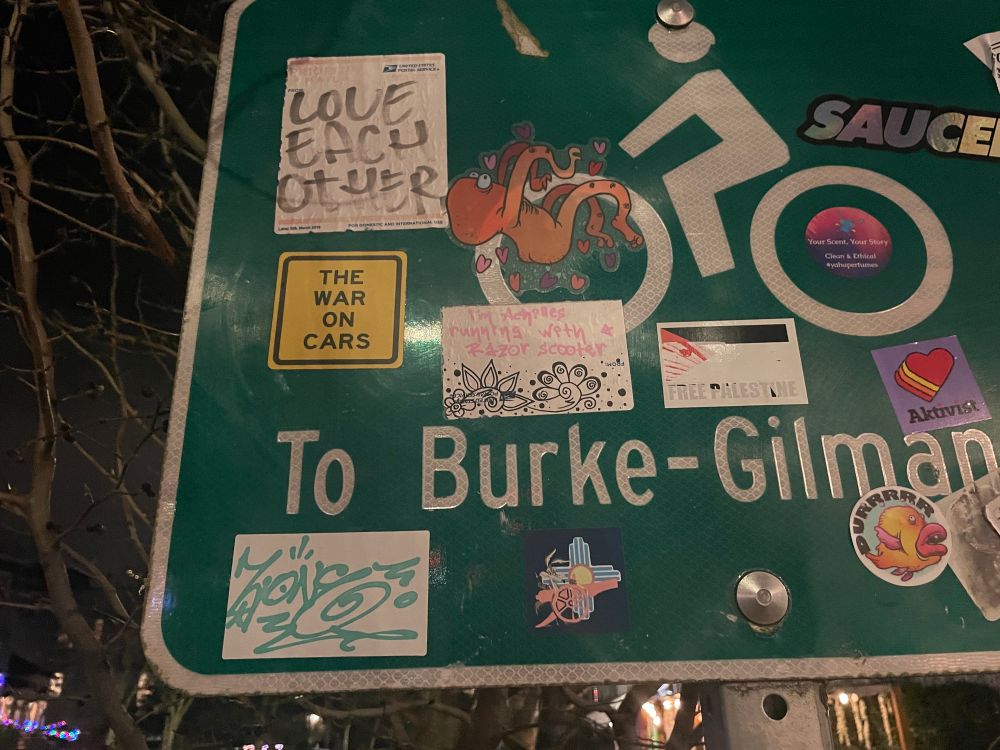 A sticker-covered sign directing to Seattle’s Burke-Gilman trail. One of the stickers is for The War On Cars.