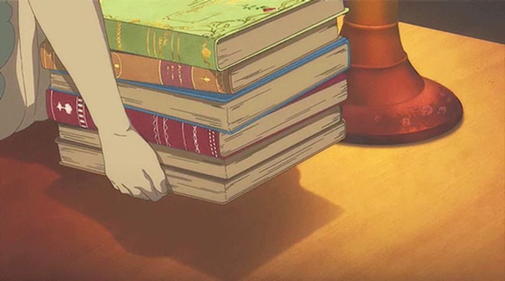 a person is pushing a stack of books on a table and one of the books has the letter t on it