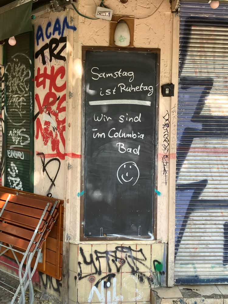 Tafel vor einem Restaurant mit der Aufschrift: „Samstag ist Ruhetag / Wir sind im Columbia Bad 🙂“