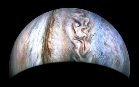 Jupiter rising up through the blacknes of space in mostly white clouds, but also some oranges, browns and blues. 