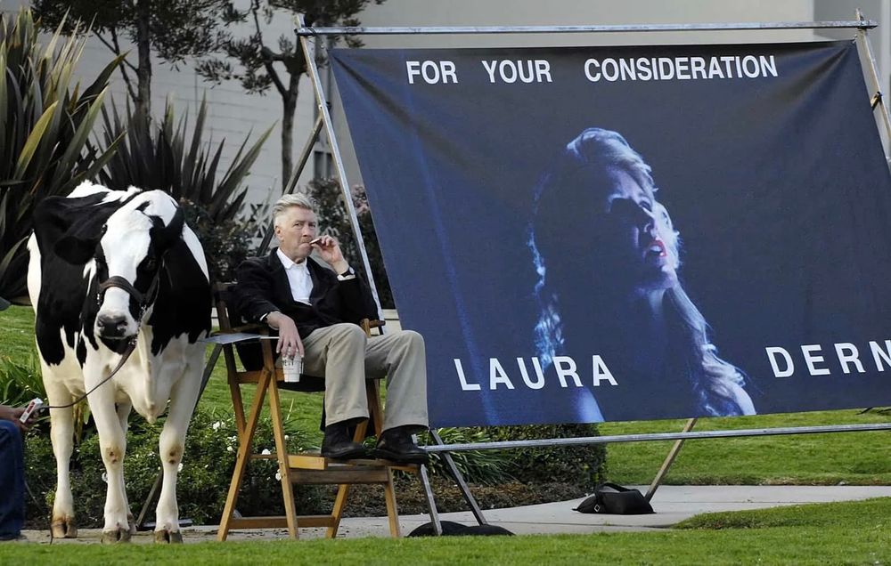 David Lynch in a chair on the side of the road with a Holstein cow (the black and white one) and a huge poster of Laura Dern that says “for your consideration, Laura Dern” in big white letters; his quite original way to promote her for a best actress Oscar to the academy