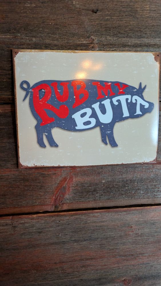 A sign with a drawing of a pig. Inside are the words "rub my butt"