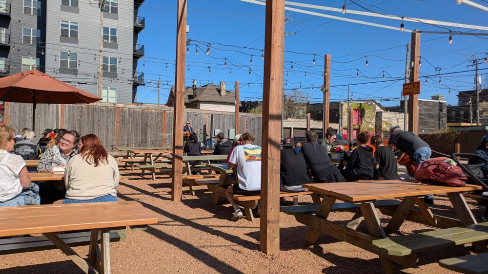 Blue sky over picnic tables with families enjoying the music and food. 