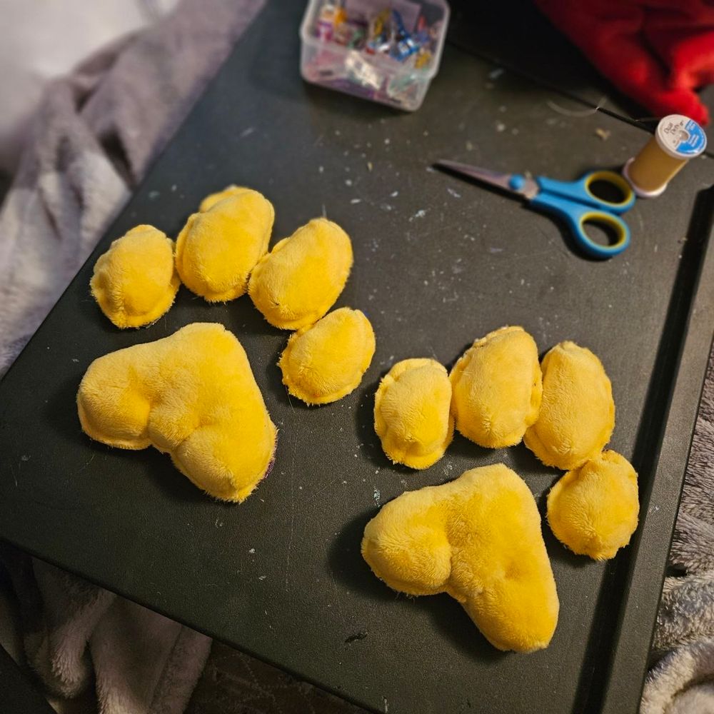 Yellow pawpads made of minky fabric sitting on a black surface.