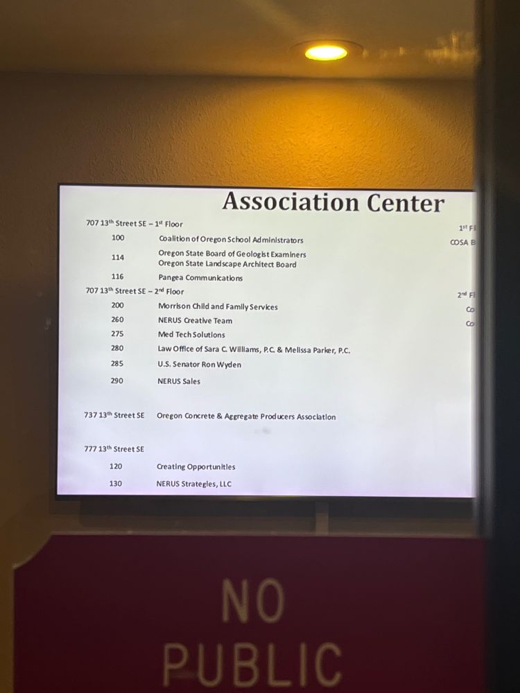 A television inside the office building has a list of suites. Senator Wyden’s office is in suite 285