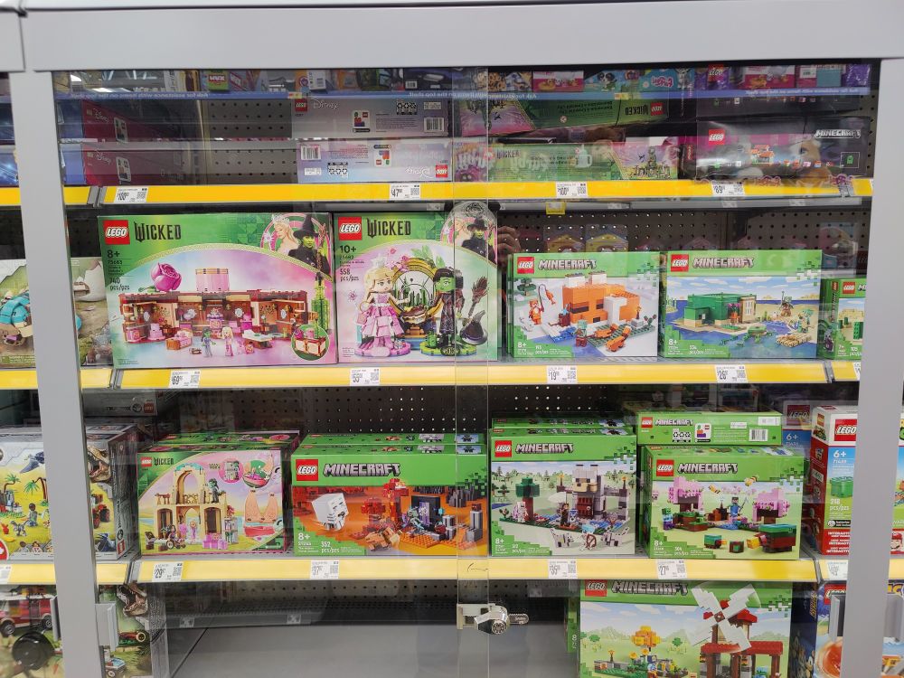 Picture of LEGO sets based on Minecraft and the musical Wicked, locked behind a glass cage to prevent theft.