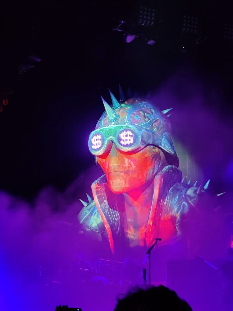 An orange cyborg skeleton structure with a combat helmet, and goggles with dollar sign lights in the sockets.