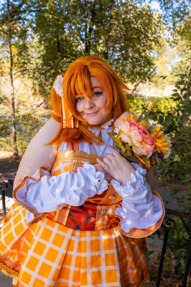Plus sized Honoka cosplayer smiling with flower bouquet 
