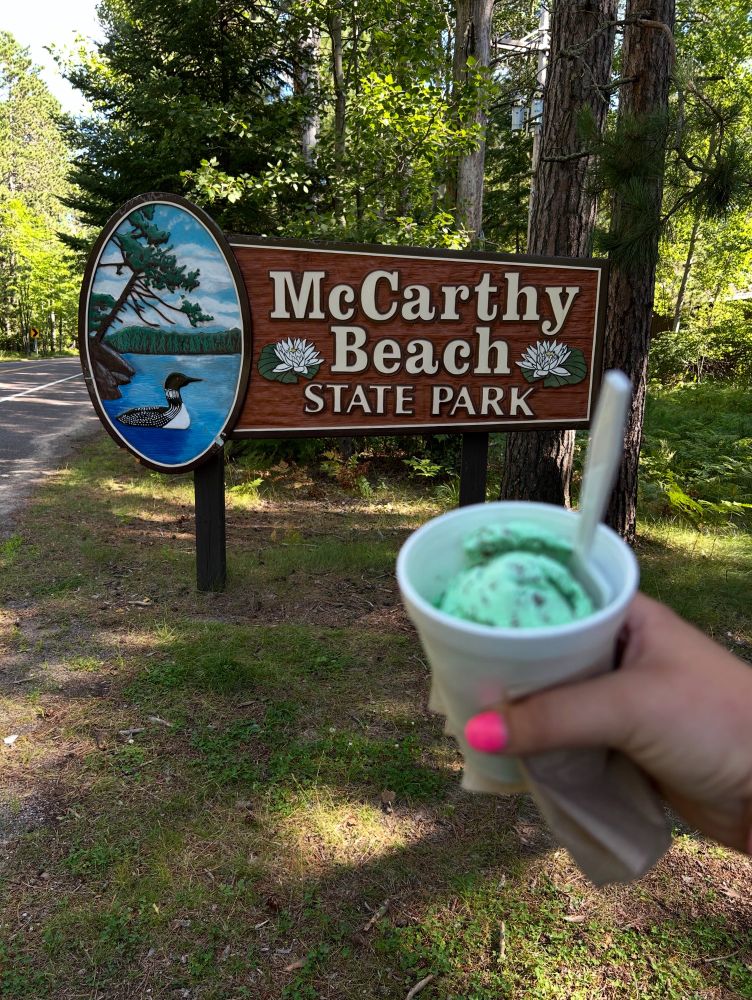 Ice cream being held up in front of state park sign 