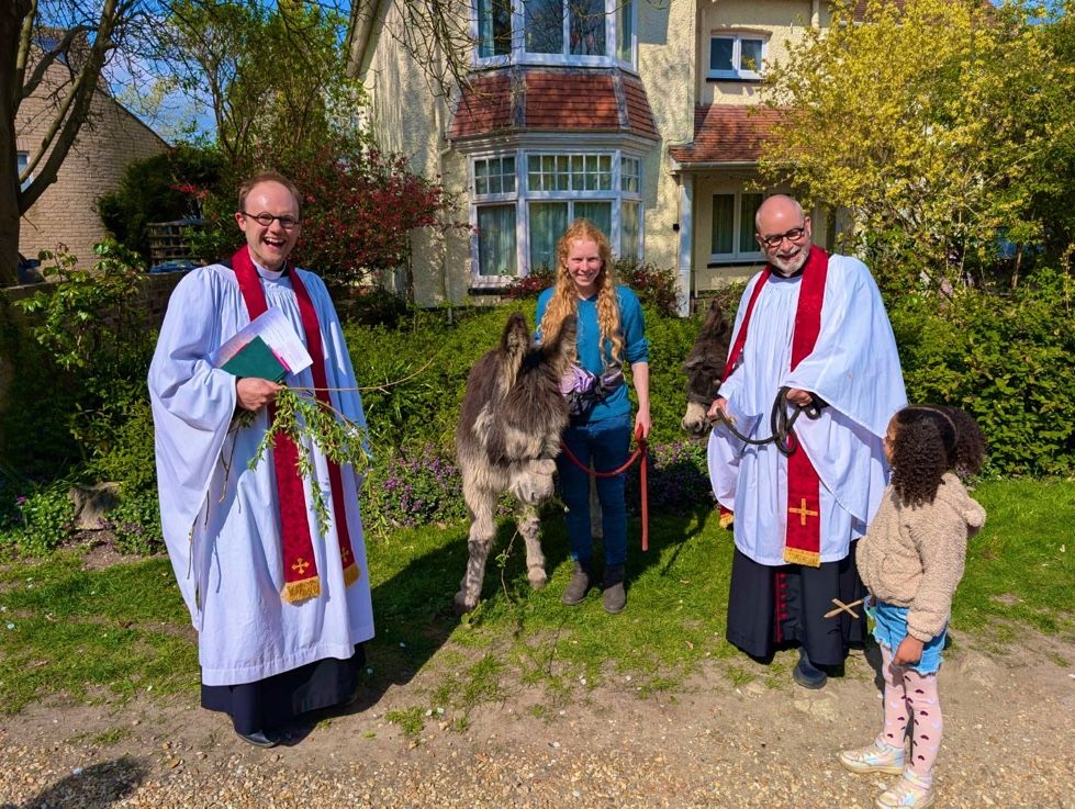 Two vicars dressed in robes and two donkeys. 