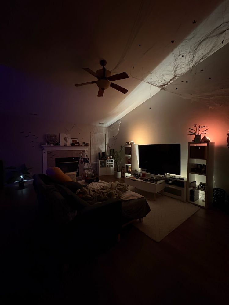 A dark living room surrounds two small lights with Halloween web decorations in the foreground 