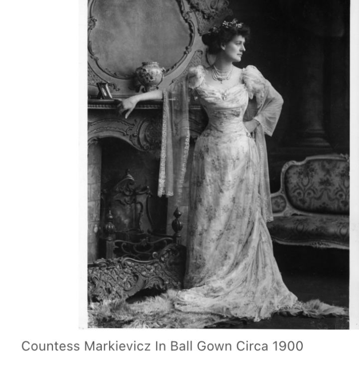 Constance Markiewicz standing in front of a fireplace, resplendent in strength and beauty, in a stunning full length gown and flowers or a tiara on her head. Circa 1990.