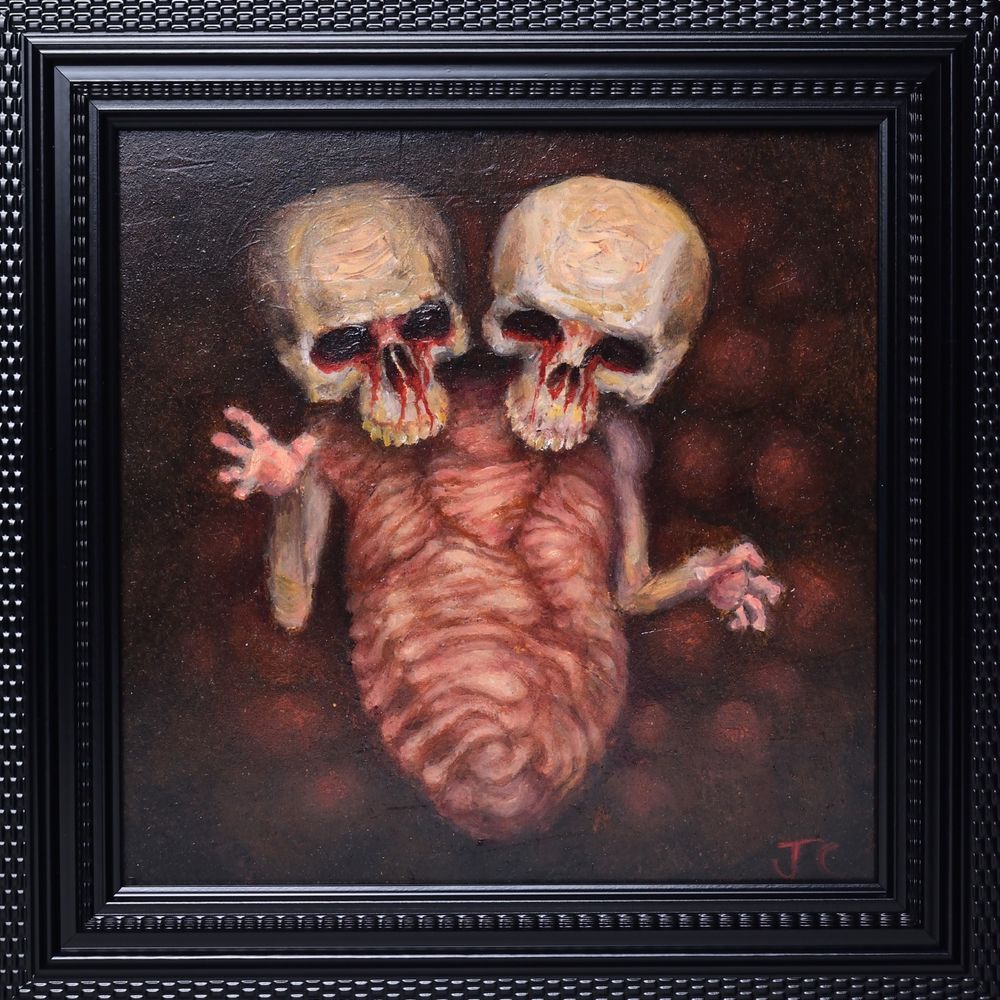 oil painting of a conjoined skull in a black frame