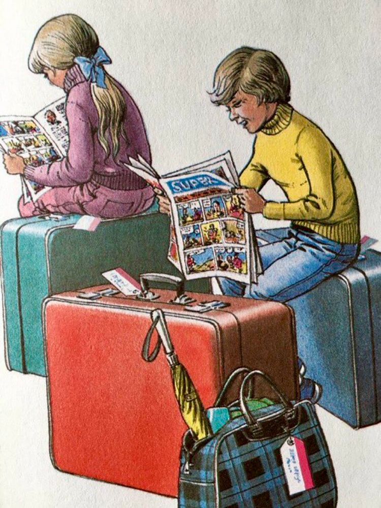 Two children in jeans and jumpers are engrossed in their comics as they sit on packed suitcases