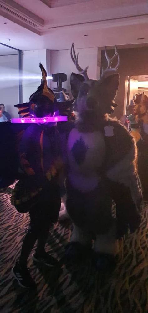 Forest cryptid and a serpent dragon posing for a photo in a dance/rave night