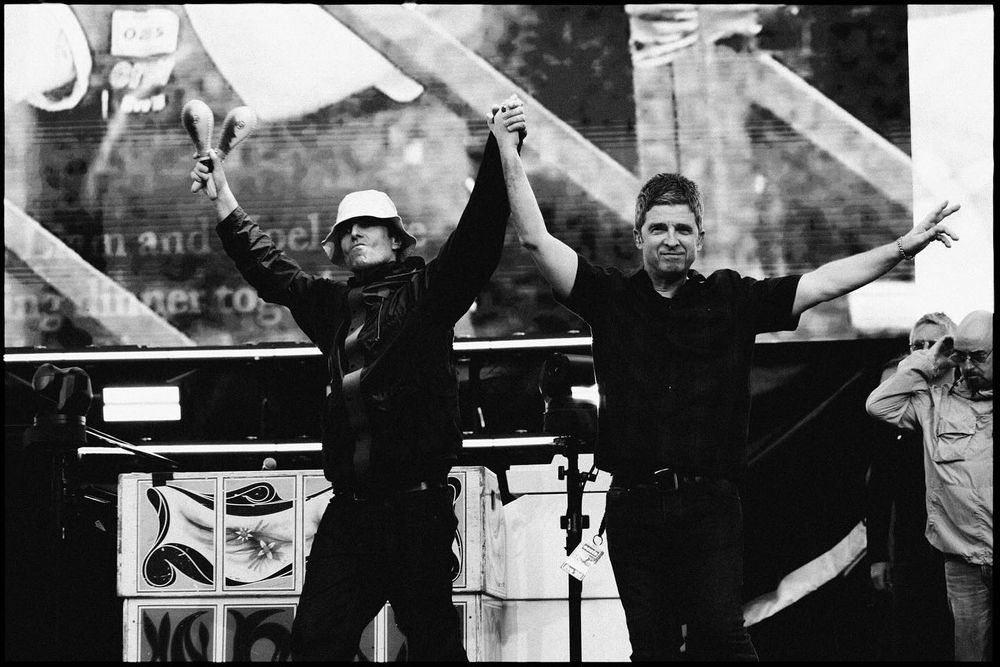 Noel and Liam Gallagher at Wembley Stadium N3 doing entering holding hands and grinning.
