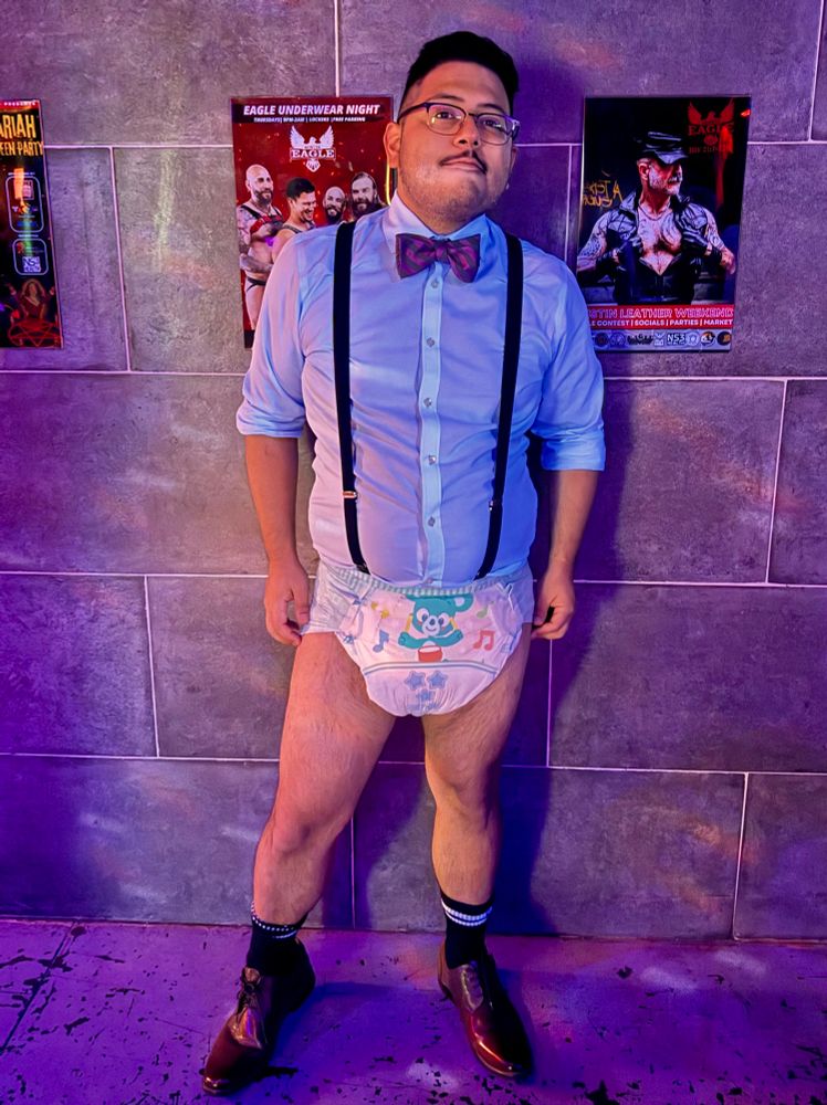 Posing at the Austin Eagle in blue dress shirt with bow tie and suspenders that are fastened to my thick diaper 