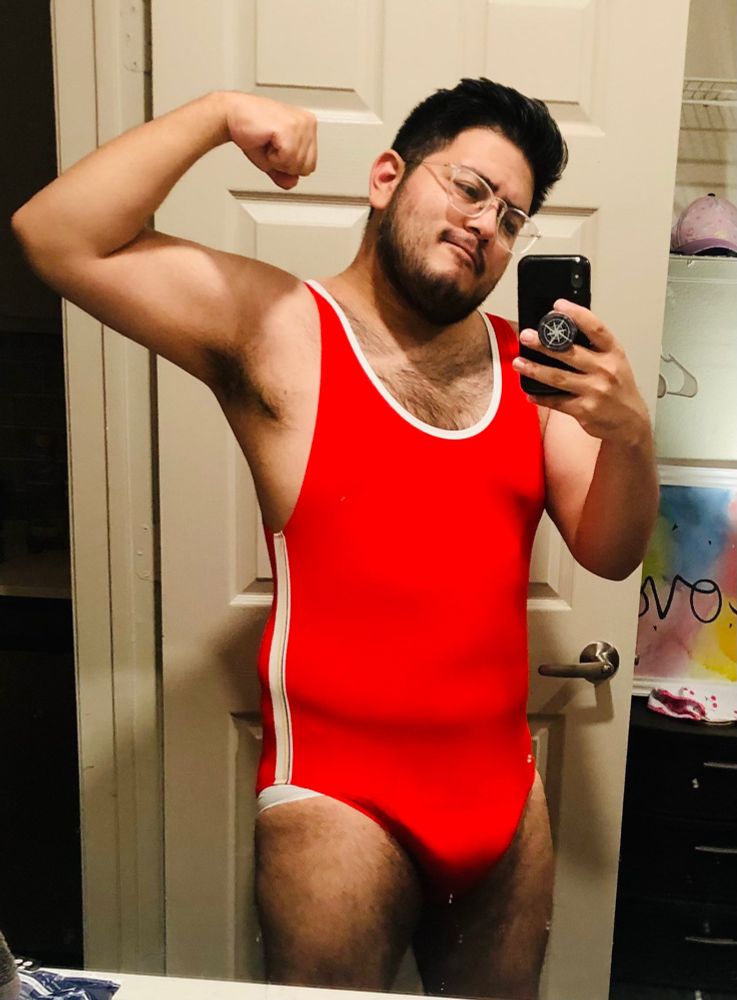 Flexing my… flabby arm, while wearing a red singlet/onesie