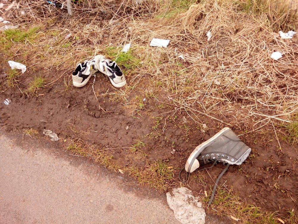 Random pair of shoes, and a single, on the side of the bike trail.