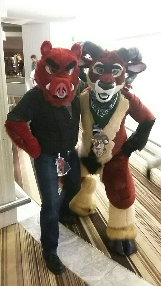 posing in fursuit, on the left a red board in black shirt and jeans, on the right is Saxon, a maroon and cream ram, at FWA 2016
