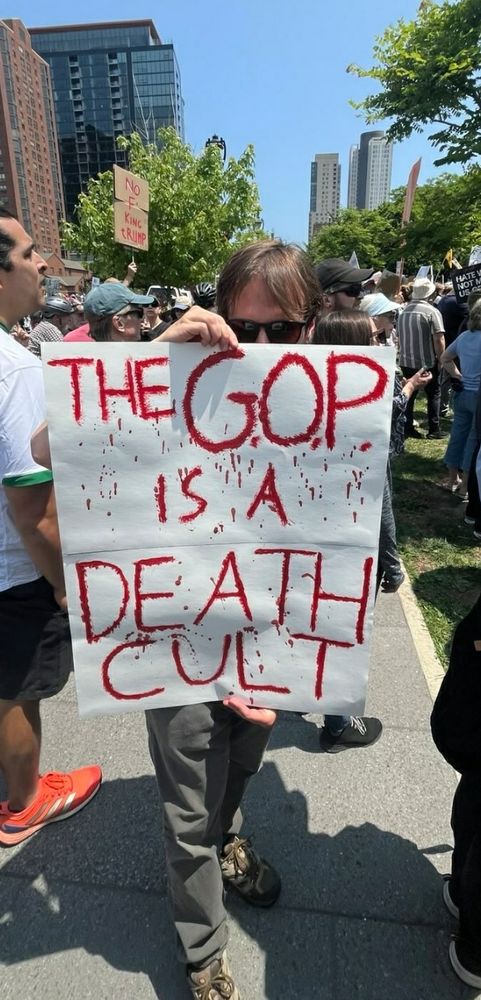 No Kings protest photo holding a sign that says "The GOP is a Death Cult".