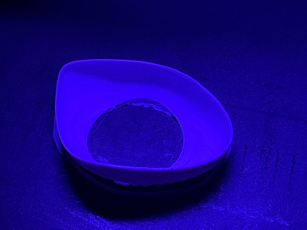 3D printed eye insert with a harsh purple lighting, still on the build plate
