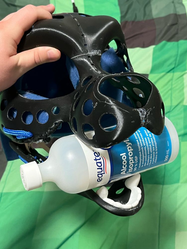 Fursuit head with a closed bottle of 99% isopropyl alcohol in its mouth
