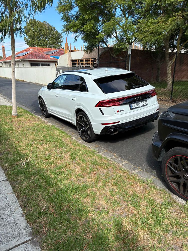 A white audio SQ8 SUV in front of a dark shade G wagon 