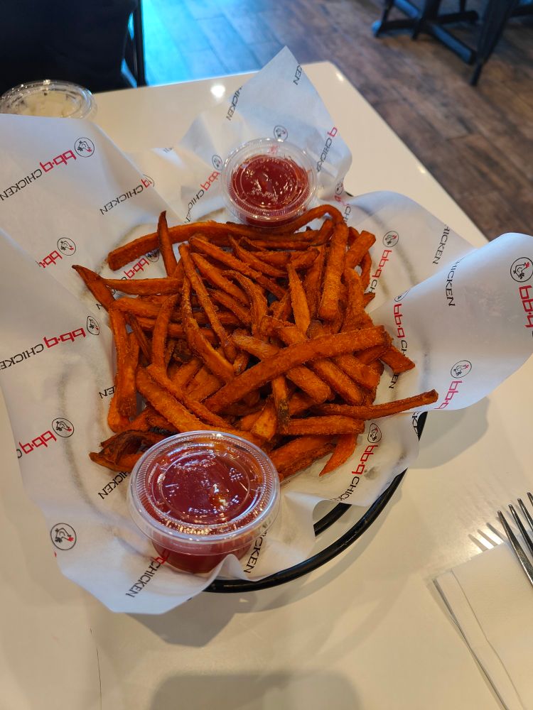 Sweet potato fries with two cups of ketchup in a basket