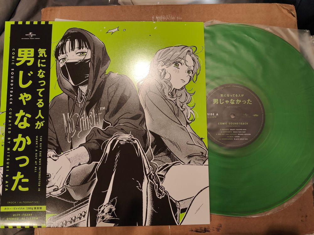 Vinyl record for the manga "The Boy She Was Interested In Wasn't A Boy At All" with the record pulled out of the sleeve for display