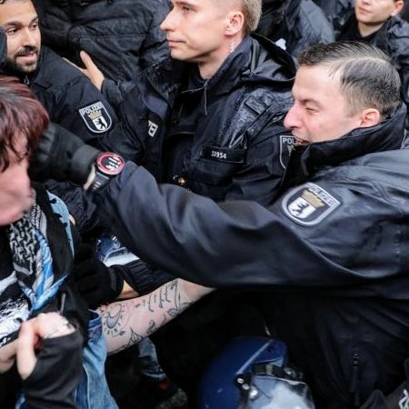 Berliner Polizist haut ohne Notwendigkeit einer Person mit seinen Kampfhandschuhen direkt ins Gesicht.
