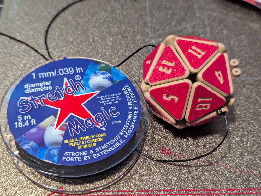 A 3d printed flexy D20 and the elastic thread that was used to string it together