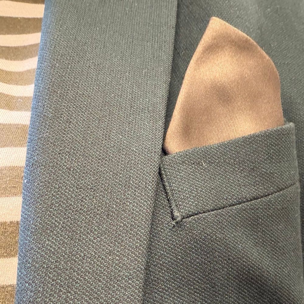 Grön kavaj med grön- och vitrandig tröja under.