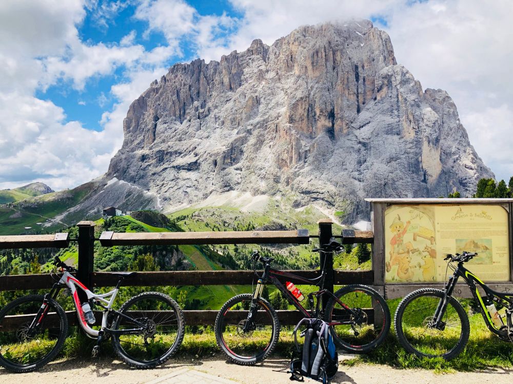 Mountain bikes against a fence with a backdrop of a spectacular rugged peak in the Dolomites.