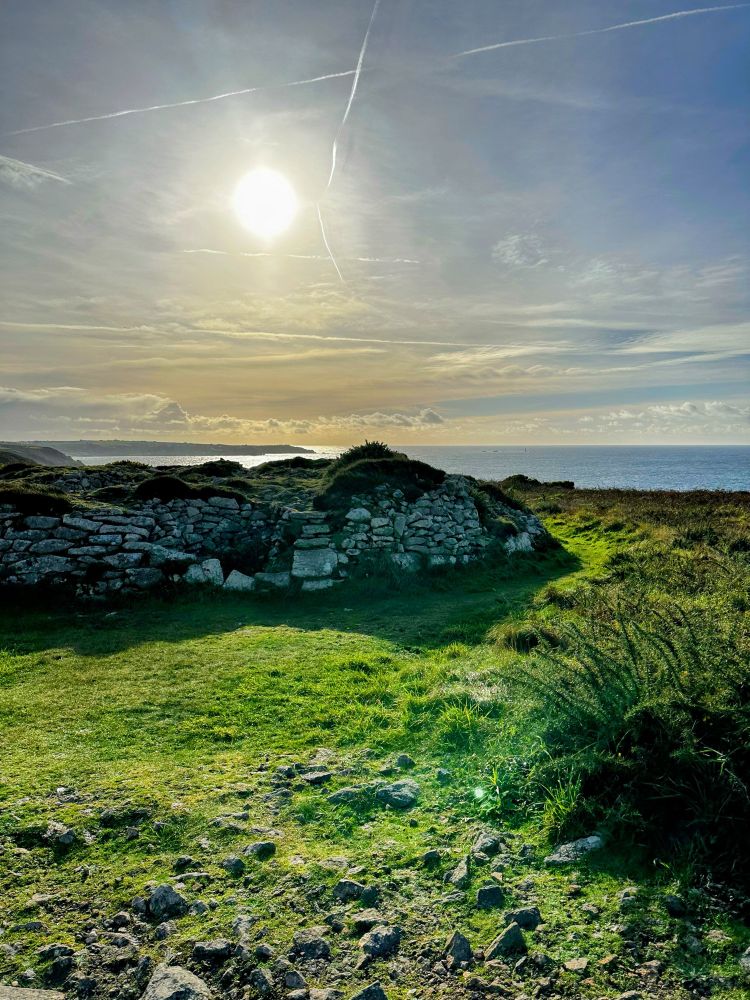 Ballowall Barrow chambered cairn in sunshine. The sea and Land’s End are on the horizon.