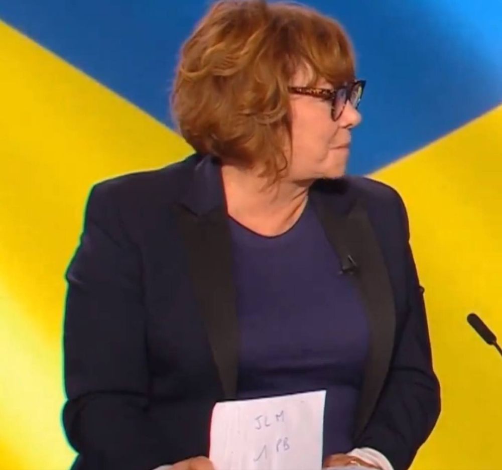 Nathalie Saint Criq qui se pense hors champ et cherche à orienter ses collègues de plateau avec un petit bout de papier écrit "jlm 1 pb"