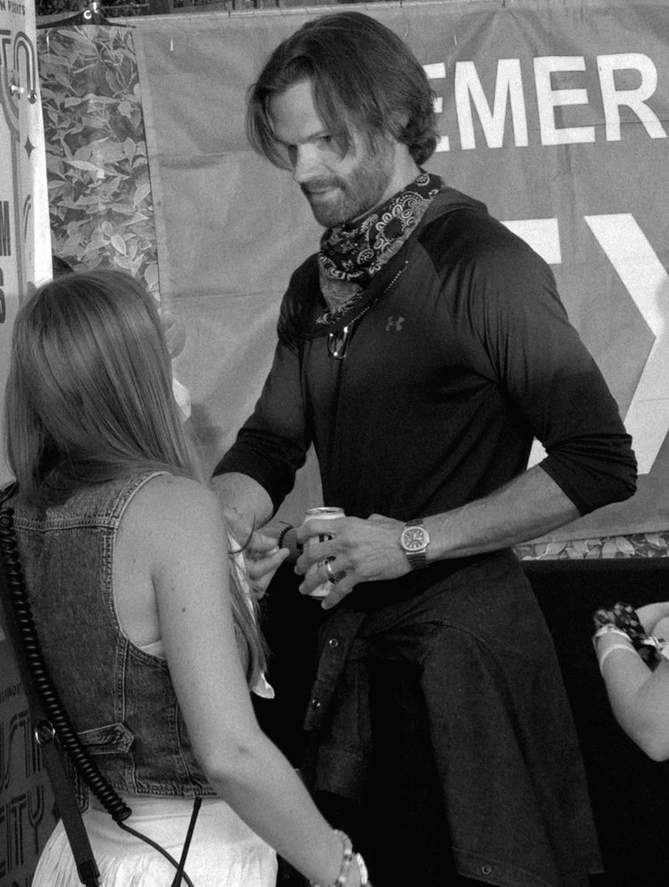 Jared Padalecki holding a can of soft drink with a bandana around his neck, and a jacket around his waist.