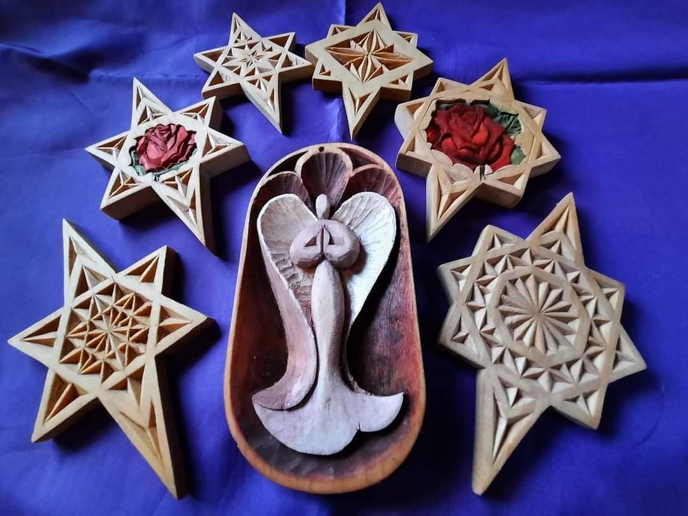 Six Chip-carved star ornaments, two with relief-carved red rose in the center. One angel relief-carved ornament, surrounded by stars.