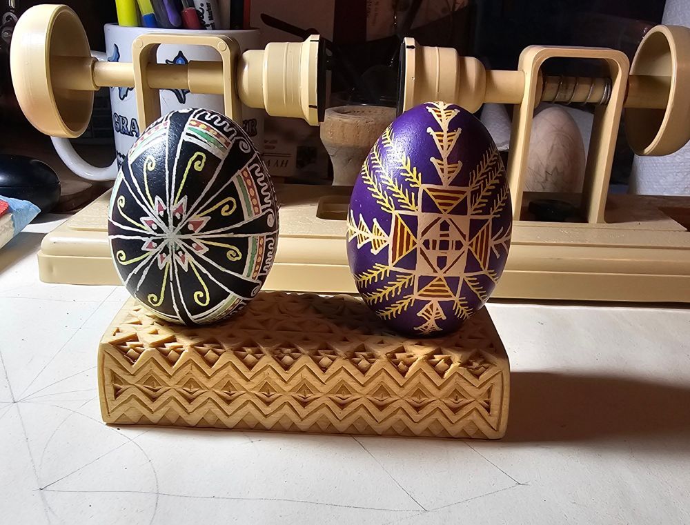 Two pysanky on a hand-carved wooden display stand.
