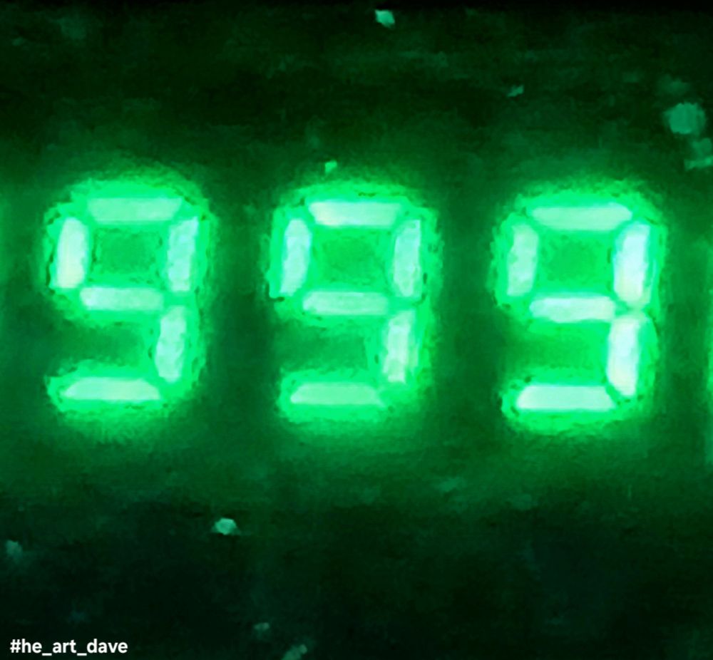 Photograph of a Glowing green numeral, nine nine nine, from a digital display. 