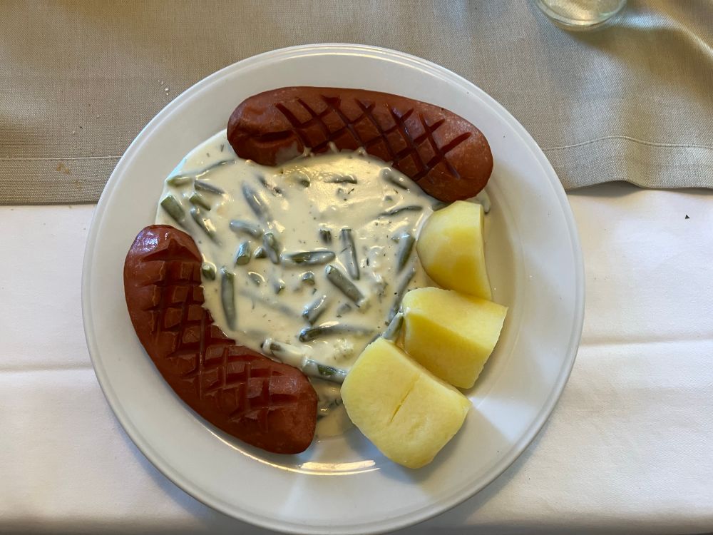 A plate of sausage, potatoes, and dill green beans