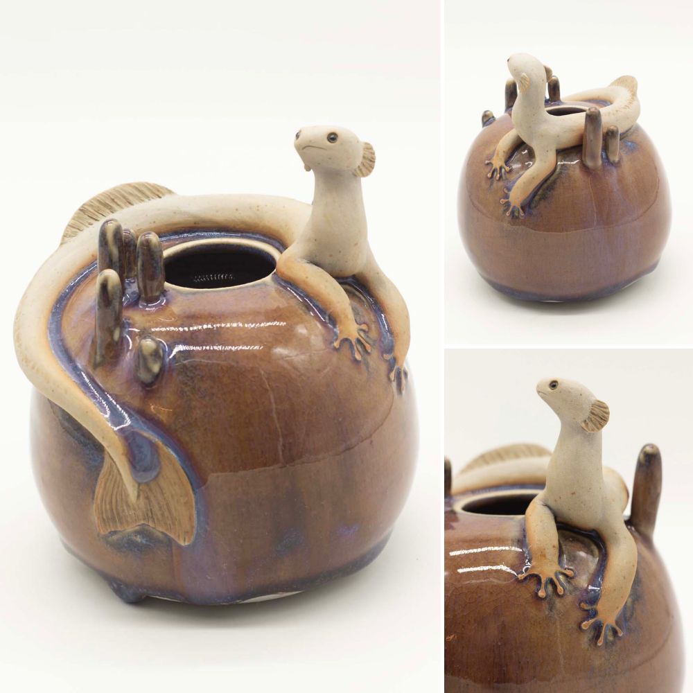 Round ceramic vessel decorated with a sculpted aquatic creature perched on top