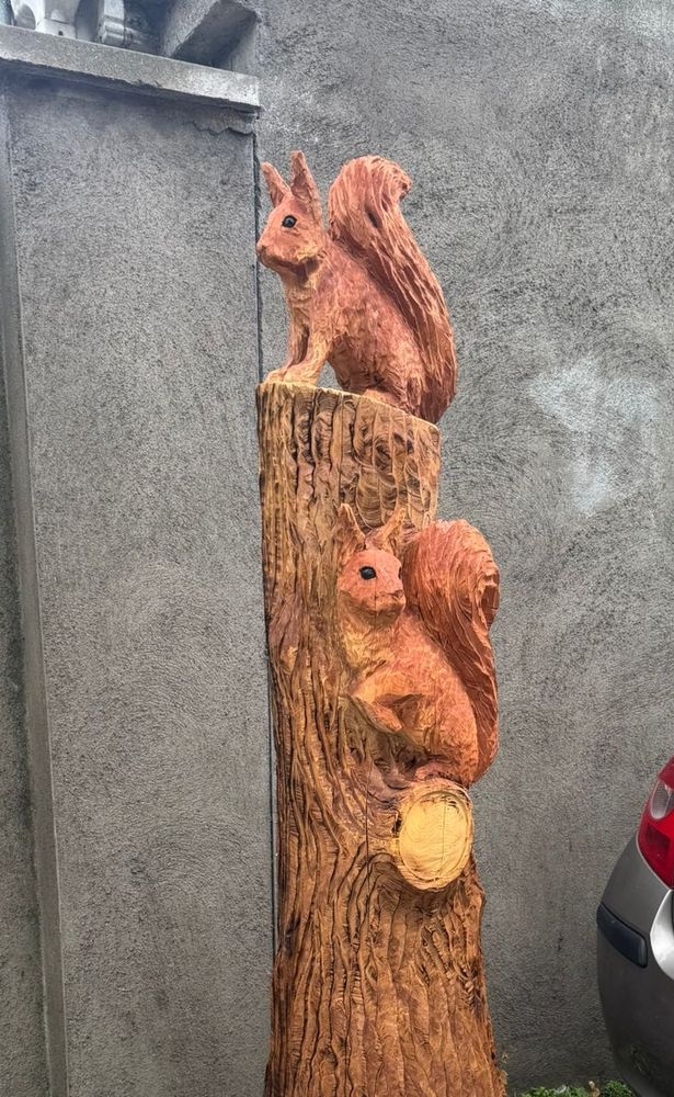 Squirrels carved from tree stump. (With a car parked on the pavement 🙄)