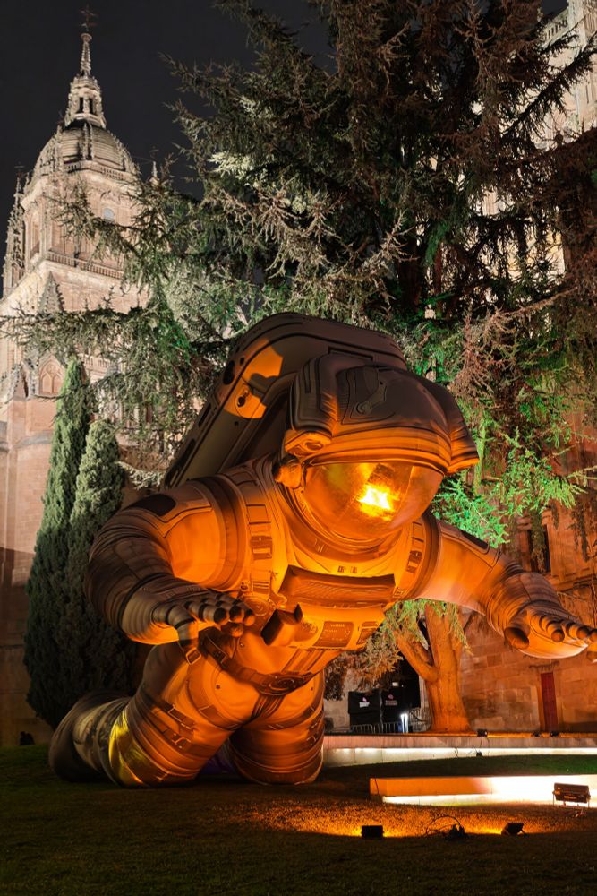 Decoración inflable gigante con forma de astronauta en primer plano y catedral de Salamanca al fondo.