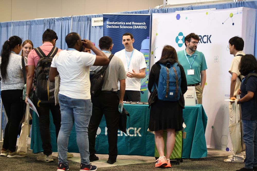 JSM 2025 attendees talk to exhibitors from Merck in the EXPO. 