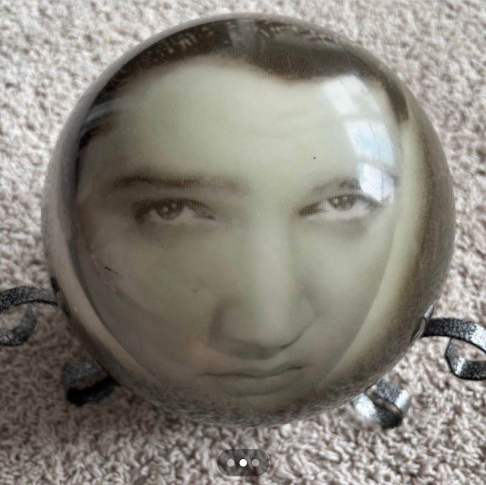 a facebook marketplace image of a bowling ball of elvis presley, allegedly with no holes. his face is warped and huge looking because he is inside of a bowling ball