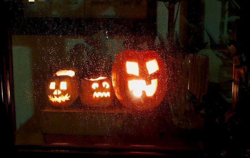 Lit up pumpkins through a rainy window 