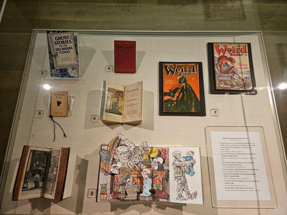 A flat glass display case containing a selection of books, ranging from the seventeenth century to roughly contemporary.